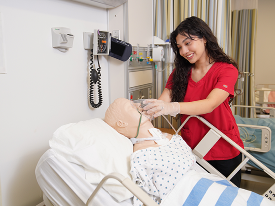 Smiling female GCC nursing student in red scrubs.